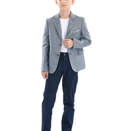 A young boy wearing a light blue gray blazer from Moustache Kids. He’s sporting a casual look with a white t-shirt, blue trousers and shiny black dress shoes. All from Moustache Kids. 