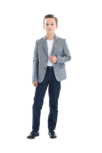 A young boy wearing a light blue gray blazer from Moustache Kids. He’s sporting a casual look with a white t-shirt, blue trousers and shiny black dress shoes. All from Moustache Kids. 