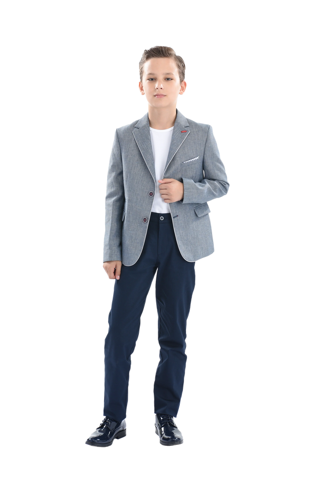 A young boy wearing a light blue gray blazer from Moustache Kids. He’s sporting a casual look with a white t-shirt, blue trousers and shiny black dress shoes. All from Moustache Kids. 