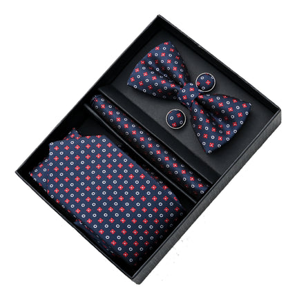 A multi colored red, white and blue bowtie, necktie, pocket square and cufflinks set from Moustache Kids. The white designs are circles, the red designs are small flowers and the backdrop of the textured clothing is navy blue. 
